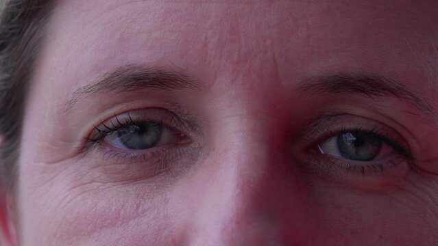 Macro Tight Close-up Of A Woman In 40s With Blue Eyes Looking At Camera. Female Caucasian Person With Wrinkles And Serious Expression