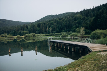 Fototapeta na wymiar wooden pier lake surrounded by mountains, Slovenia. The concept of summer holidays, holidays 