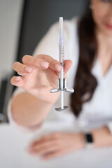 Specialist cosmetologist demonstrates a syringe with a rejuvenating substance