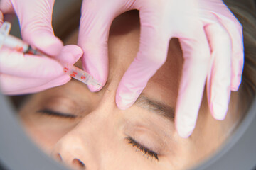 Cosmetologist makes beauty injections to a blonde woman