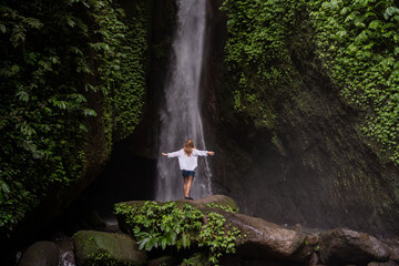 Waterfall in tropical jungle and alone woman tourist. Leke Leke waterfall in Bali, Indonesia.