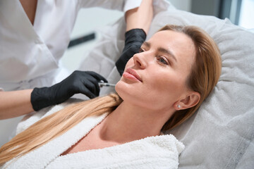 Obraz na płótnie Canvas Beautiful female receives a rejuvenating chin injection