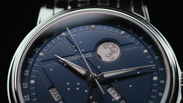 closeup view of rotating luxury swiss watch with moonphase and running second arrow. Macro.