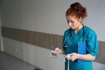 Nurse holding remote supervisor control panel of the adjustable bed in chamber