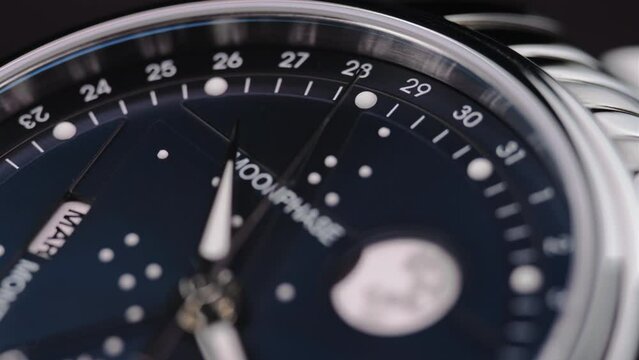 closeup view of rotating luxury swiss watch with moonphase and running second arrow. Macro. 