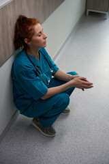 Tired female doctor near the wall in the hospital