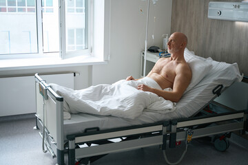 Sick man resting in bed in hospital ward