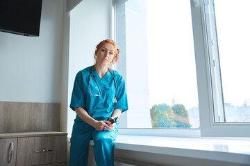 Female doctor sitting on the windowsill in hospital