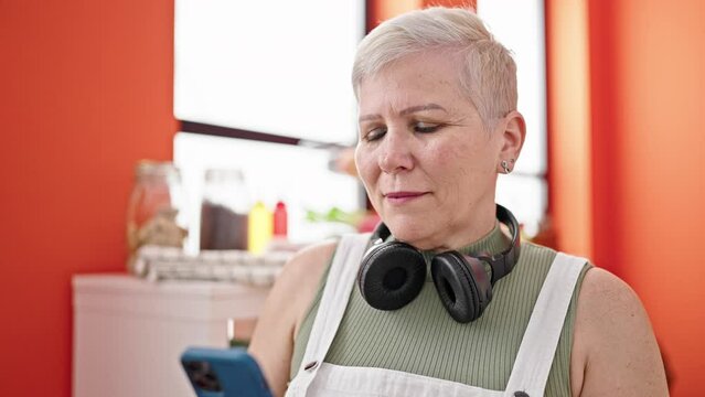 Middle age grey-haired woman smiling confident making selfie by the smartphone at dinning room