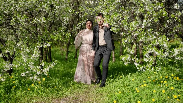 romantic walk of loving couple in blooming garden in spring day, full-length shot, man and woman
