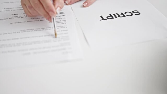 Middle age grey-haired woman reading movie script on table