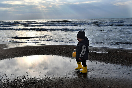 Little boy walking down severe baltic sea in autumn season