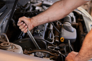 Auto mechanic working on car engine in mechanics garage. Repair service. authentic close-up shot
