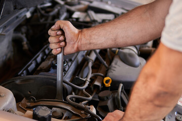 Fototapeta na wymiar Auto mechanic working on car engine in mechanics garage. Repair service. authentic close-up shot 