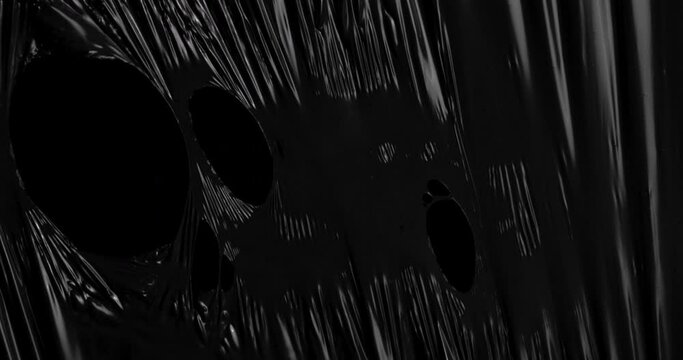 Unleash your creativity as stretched plastic film weaves its intricate patterns against a backdrop of infinite blackness, its texture reminiscent of the rhythmic folds.