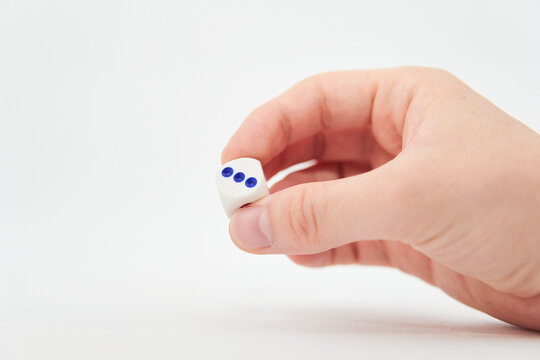 Male hand throwing white dice in the air on white background. Game with dice, Hazard, Cho-Han Bakuchi, Under-Over 7, Mexico, Shut the Box. Gambling luck concept: bet, risk, have luck, win. lucky
