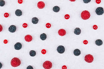 Various fresh berries on light textured table, top view. Red and black raspberries, red currants berries. Pattern, close-up shot.