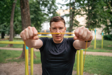 Middle age man doing strength exercises with resistance bands outdoors in park 