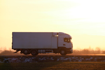 Cargo truck driving on highway hauling goods in evening. Delivery transportation and logistics...