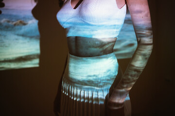 Young adult woman 20 years old with projected image of ocean or see in neon colors