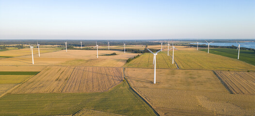Wind turbines creating environmental friendy renewable electricity on a crop field by the coast at sunset
