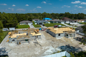 Professional builders working on roof construction of unfinished suburban home with wooden frame...