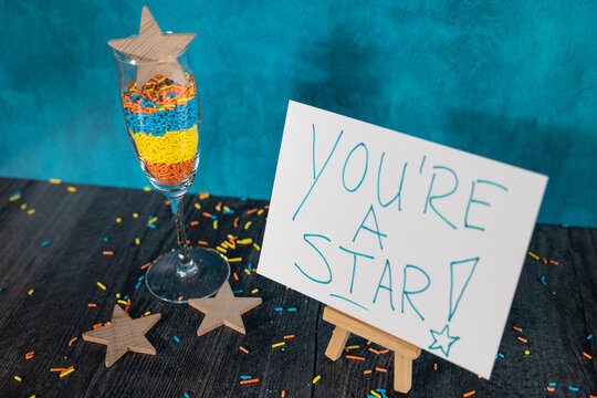You're a star hand written on white sign with wooden stars and colorful confetti 