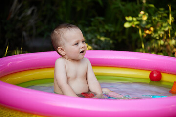 cute baby girl swimming in kid inflatable pool