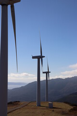Image of three windmills on top of a mountain, with views to the background in Carnota (Galicia, Spain). Upright image.