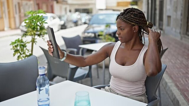 African american woman make selfie by touchpad sitting on table at coffee shop terrace