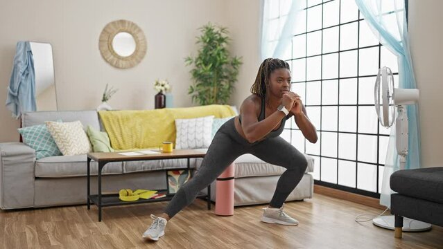 African american woman wearing sportswear doing legs exercise at home