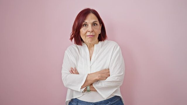 Middle age woman standing with arms crossed gesture pointing to camera smiling over isolated pink background