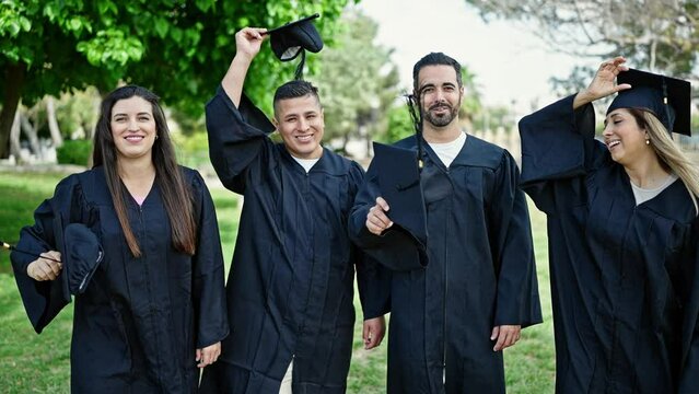 Group of people students graduated smiling confident throwing cap to air at university campus