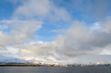 View to calm water surface of lake Sevan and snow capped mountains in distance. Picturesque landmark of Armenia