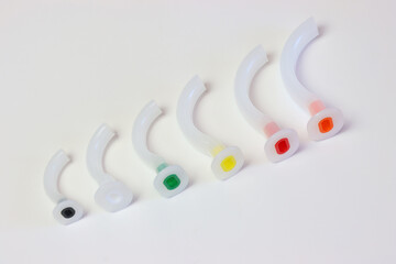 Oropharyngeal airway cannula in a white surface aligned by the size of each cannula. Small to big size. 0 to 5 size of a guedel cannula 
