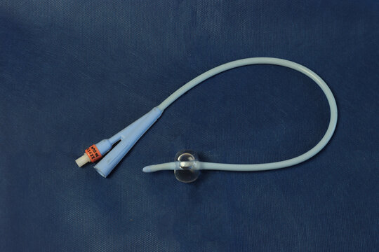 Foley catheter in a dark blue background with a insuflated balloon.