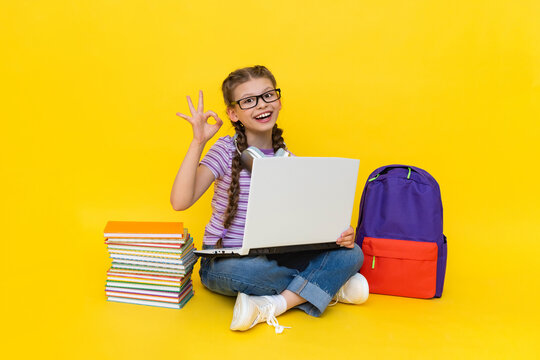 A child wearing headphones with a laptop shows the OK sign. A young girl with books and a backpack does homework online with a teacher. Yellow isolated background.