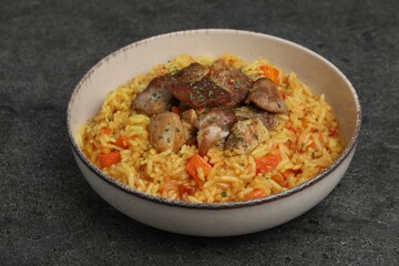 Delicious pilaf with meat on grey textured table, closeup