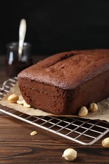 Delicious chocolate sponge cake and nuts on wooden table, closeup