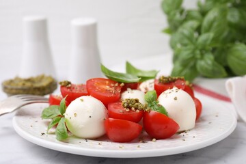 Tasty salad Caprese with tomatoes, mozzarella balls and basil served on table, closeup