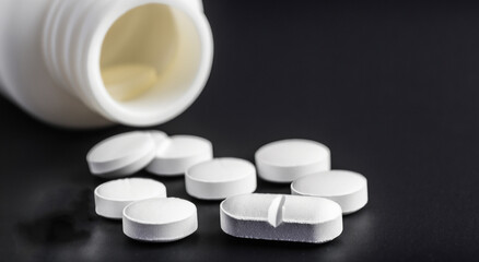white jar with watered pills on black background. drugs and drugstore concept