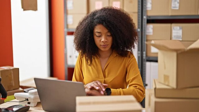 African american woman ecommerce business worker using laptop looking watch relaxing at office