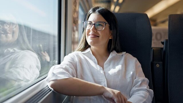 Young beautiful hispanic woman smiling happy looking through the window at train station