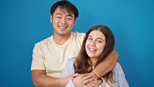 Man and woman couple smiling confident hugging each other over isolated blue background