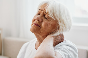 Elderly woman severe neck pain sitting on the sofa, health problems in old age, poor quality of...
