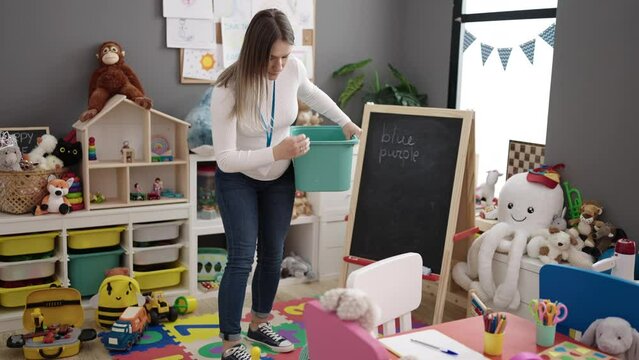Young pregnant woman preschool teacher collecting toys suffering backache at kindergarten