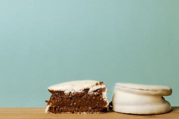 Alfajor, traditional Argentinian sweet, cut in half on wooden board and turquoise background