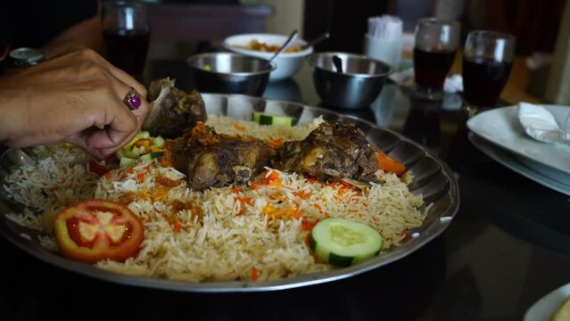 Close-up hands picking nasi mandi to eat showcases the intimate act of selecting and enjoying this flavorful dish. Nasi mandi is a traditional Middle Eastern rice dish that is known for its fragrant