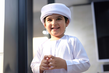Happy boy in Kandura looking far with business, mall or school education background. Emirati Arabic son ideal for Young Middle Eastern concept. 