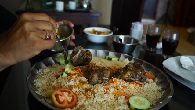Close-up hands picking nasi mandi to eat showcases the intimate act of selecting and enjoying this flavorful dish. Nasi mandi is a traditional Middle Eastern rice dish that is known for its fragrant